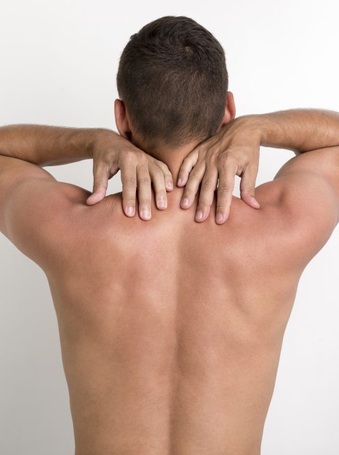 rear-view-shirtless-man-having-back-pain-standing-against-white-wall