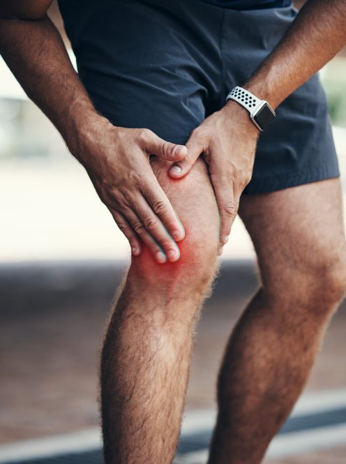 Closeup shot of an unrecognizable man holding his knee in pain while exercising outdoors.