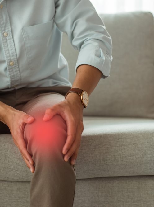 The young man sat on the sofa in the living room at home and was holding his knees with both hands. He was suffering from knee pain and was unhappy in daily life. He had to be healed quickly.